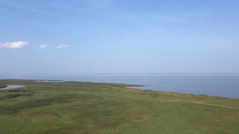 Aerial view flying forwards over a grassy marsh and towards a large lake.  Stock Footage 275409843