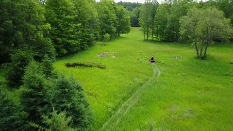 Aerial View Flying Green Area Showing ATV Rider Driving Below 3 Video stock 77317841