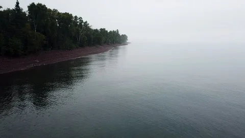 Aerial view: Flying low over lake next to shoreline in fog Stock Footage 100558215