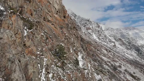 Aerial view flying next to steep cliffs covered with snow in a mountain gorge on Stock Footage 132794107