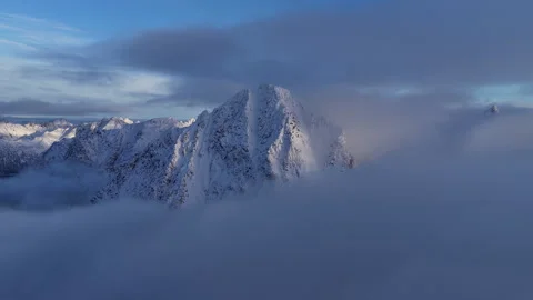 Aerial view flying over clouds and snow-capped mountain peaks, Norway Видео 343936392