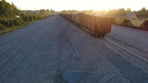 Aerial view. Flying over empty railroad cars for gravel on the rails at sunset. Stock Footage 94497372