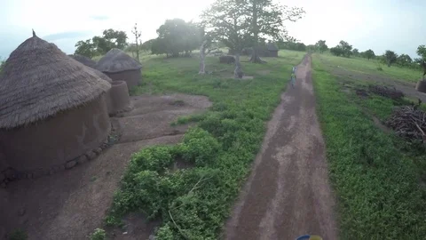 Aerial view - Flying over huts, women carrying water and grinding Stock Footage 83603622
