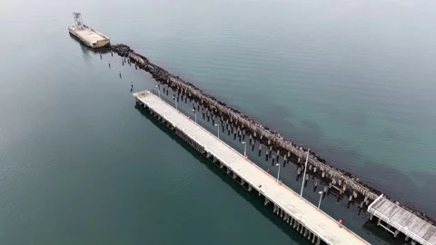 Aerial view flying over a long pier in the ocean Stock Footage 337811807