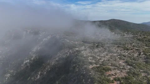 Aerial view flying over mountain peaks in clouds near Poulithra Greece with mist Video stock 302069358