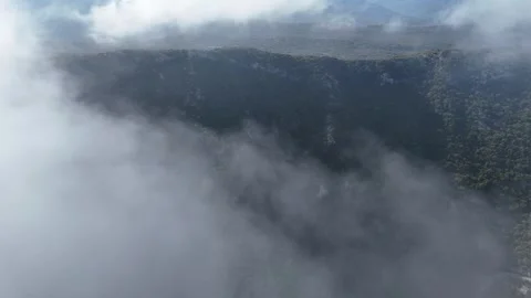 Aerial view flying over mountain peaks in clouds near Poulithra Greece with mist Video stock 302070147