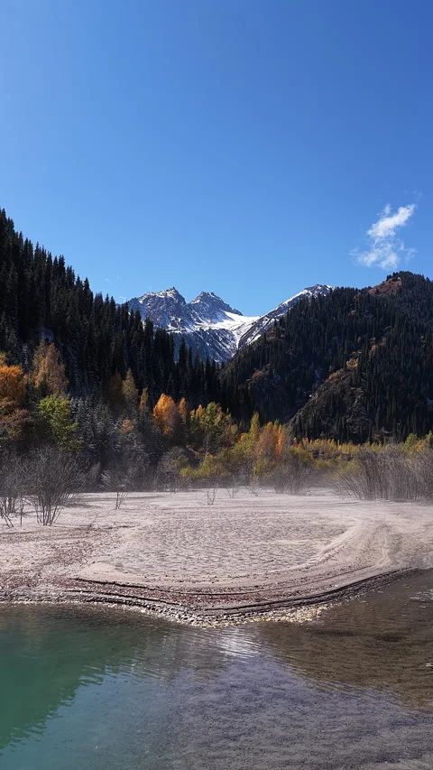 Aerial view flying over a mountain Issyk's lake and autumn forest, Kazakhstan Stock Footage 344756525