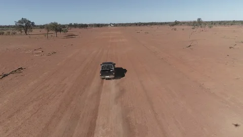Aerial view flying over moving car on dirt road outback Stock Footage 92518311