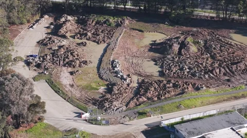 Aerial view flying over muddy construction site with heavy machinery tracks Stock Footage 341271955