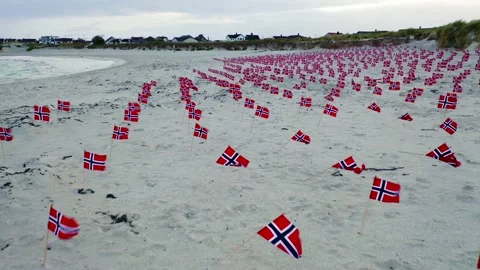 Aerial view flying over multiple Norway flags on sandy beach coastline Stock Footage 133850834