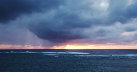 Aerial view flying over ocean reef and waves into dramatic sunset storm Stock Footage 63063670