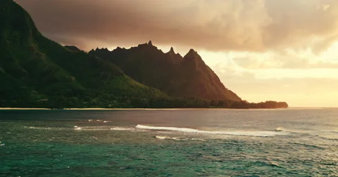 Aerial view flying over ocean reef and waves into dramatic sunset on Kauai Stock Footage 63573433