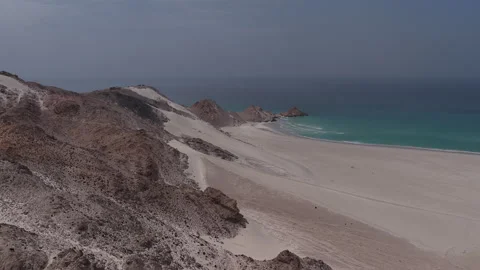 Aerial view flying over a remote sandy beach and turquoise ocean Stock Footage 334683689