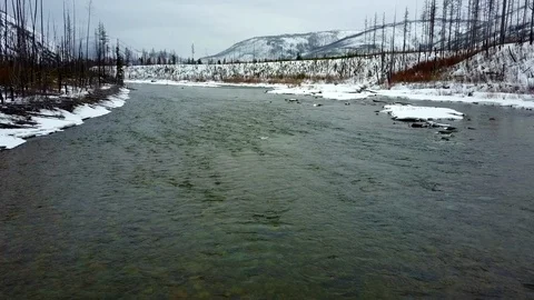 Aerial view: Flying over river in the winter with mountains in background Stock Footage 100568312