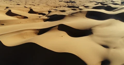 Aerial view flying over sand dunes in desert at sunset Vidéo 89509433