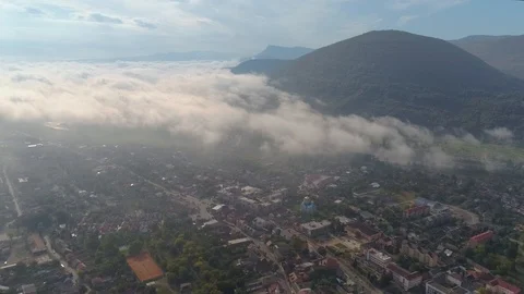 Aerial View: Flying over the small city covered by clouds. Aerial camera shot Vídeo Stock 103265019