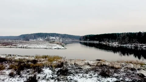 Aerial view flying over snow-covered lake with distant village Video stock 330272533