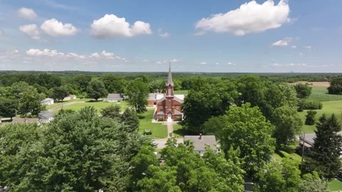 Aerial view flying over trees in a small town toward an old catholic cathedral c Stock Footage 312246069