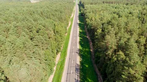 Aerial view flying over two lane forest road Stock Photos