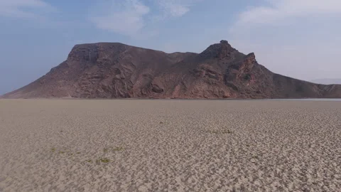 Aerial view flying over vast sandy expanse towards a solitary mountain, Socotra Vidéo 335206805