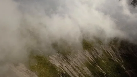 Aerial view. Flying sideways in front of big white clouds up in the mountains Stock Footage 91445987