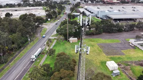 Aerial view flying up telecommunications cell tower with traffic Stock Footage 342325964
