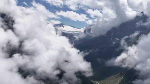 Aerial view flying through clouds revealing snowy mountain peaks Stock Footage 317656169