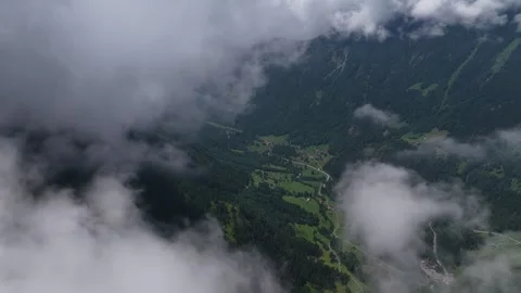Aerial view flying through clouds over a green mountain valley Stock Footage 317719654