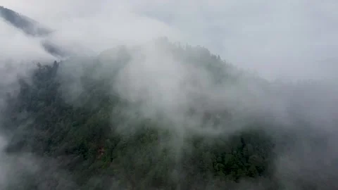 Aerial view flying through clouds towards a lush mountain forest Vidéo 331899584