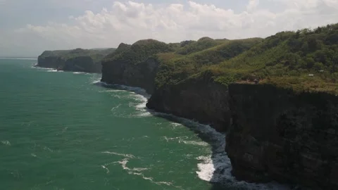 Aerial view of flying towards massive cliffs jutting down into the sea. Stock Footage 293714616