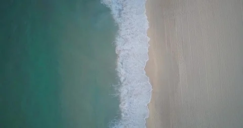 Aerial view of foamy waves reaching towards a sandy beach Stock Footage 122391273