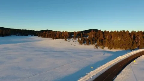 Aerial view of a forest meadow covered in snow, next to a road Stock Footage 71879253