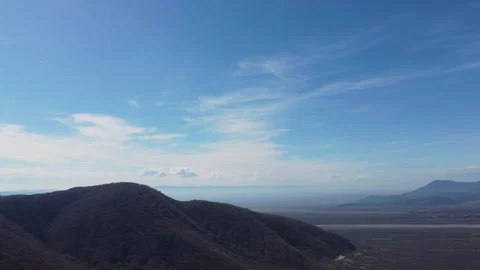 Aerial View of Forested Hills Overlooking a Misted Plain. A wide-angle dron.. Stock Footage 332004841