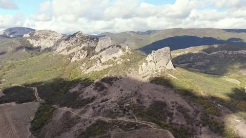 Aerial view of a forested mountain range under a blue sky with white clouds Stock Footage 258477865