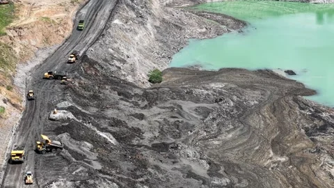 An aerial view of a former coal mine pit filled with blue water shows haul .. Stock Footage 343247214