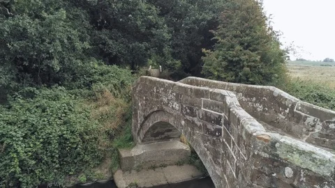 Aerial view, forward move. Drone fly towards old small sandstone roman bridge Stock Footage 95540129