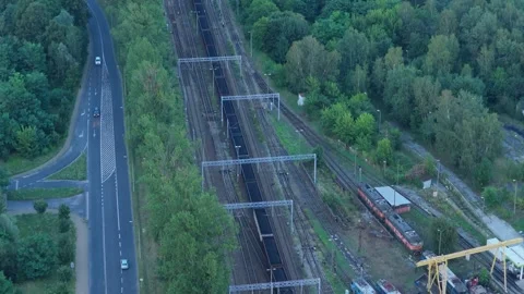 Aerial view of a freight train and highway traffic surrounded by green trees Stock Footage 348198598