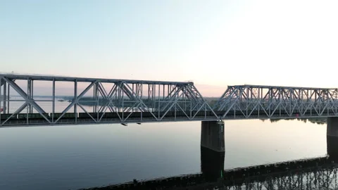 Aerial view. A freight train with many wagons travels over a railway bridge  Stock Footage 218624086