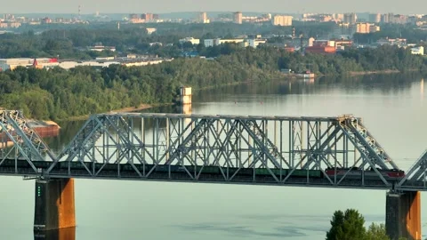 Aerial view. A freight train with many wagons travels over a railway bridge  Stock Footage 234538586