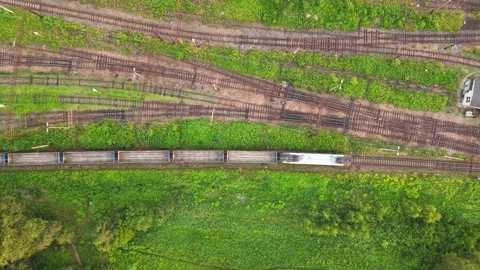 Aerial view of freight train moving along railway tracks surrounded by greenery 스톡 동영상 338351381