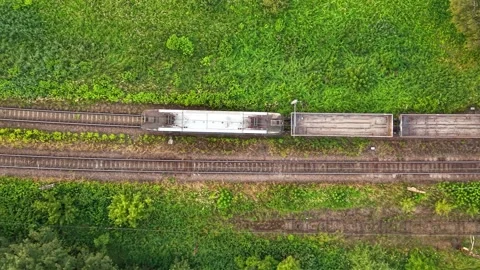 Aerial view of freight train moving along railway tracks surrounded by greenery 스톡 동영상 338351496