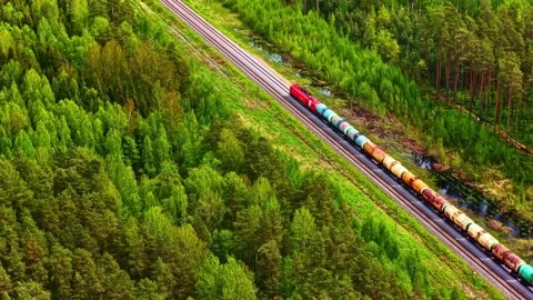 Aerial view of a freight train moving through a forest in Latvia. Stock Footage 340602441