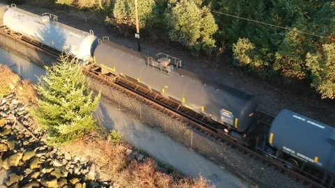 Aerial view of freight train passing by with walking trail and rocky beach Video stock 101861720