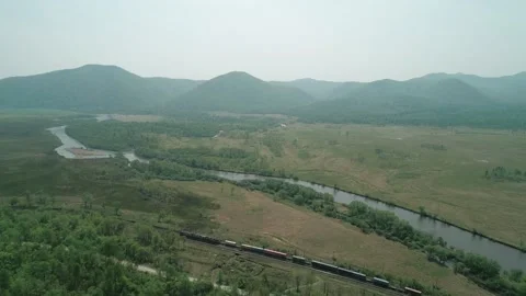 Aerial view of a freight train passing by the forest and a river. Beautiful Stock Footage 171693090