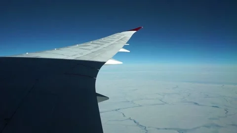 Aerial: view of full plane wing, blue sky and frozen sea near Canada Stock Footage 235650449