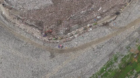 Aerial view of garbage trucks dumping waste in a bali landfill Stock Footage 327813280