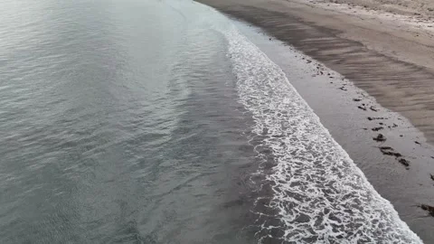 Aerial view of gentle waves along sandy beach shoreline Vidéo 332679758