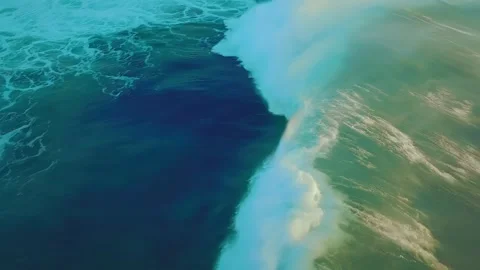 Aerial view of a giant emerald wave breaking in the ocean creating white foam Stock Footage 343696378