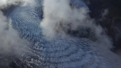 Aerial view of a glacier flowing through a mountain valley with clouds 스톡 동영상 333205598