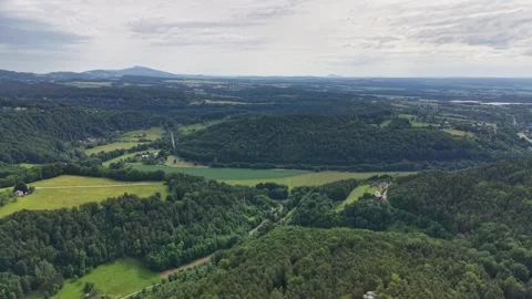 Aerial view gliding over rolling hills, dense forests, and patchwork fields Stock Footage 346261523